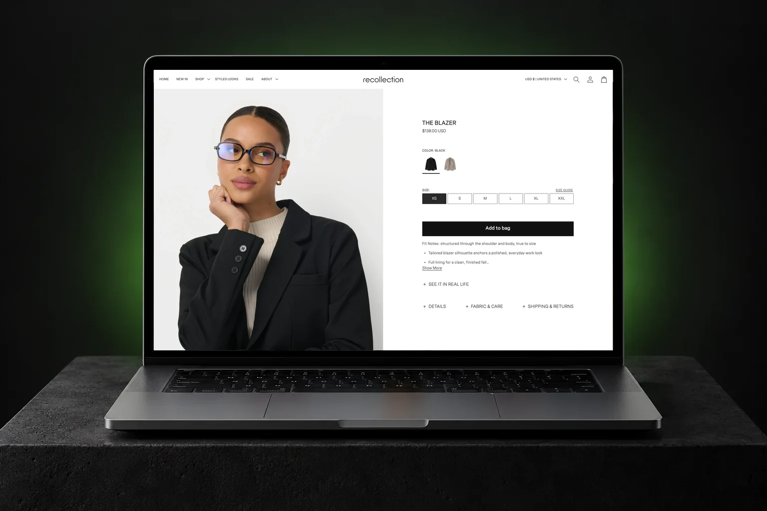 Recollection Shopify store on a laptop, showing The Blazer product page with a model in black glasses, black and taupe image swatches, sizes XS to XXL and an Add to bag button | EVDEV